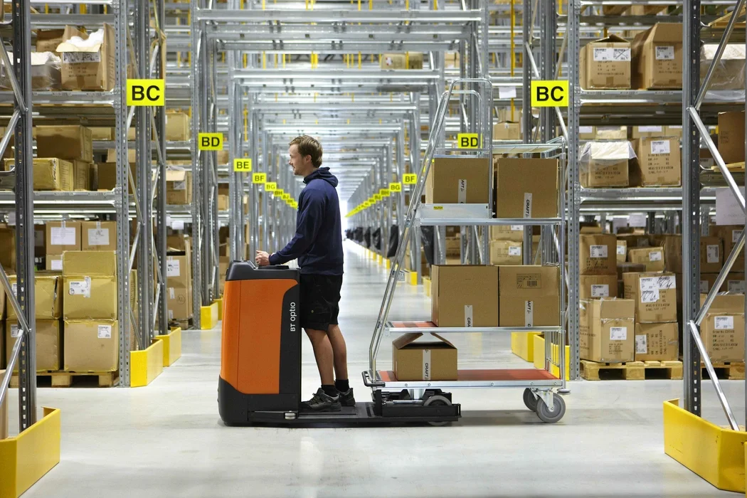 Tracto TSE150, ride on tow tractor. Application photo with order picking in warehouse environment. 