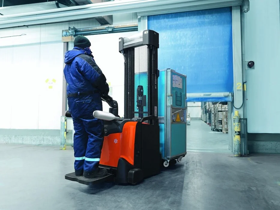 BT Staxio SPE160L, electric stacker with elevating support arms, platform, and side guards. Application photo in cold store loading bay.