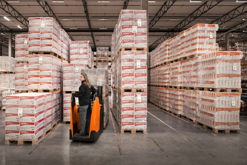 BT Staxio SPE200DN, electric stacker with double load handling and fixed side guards. Application photo in warehouse environment.