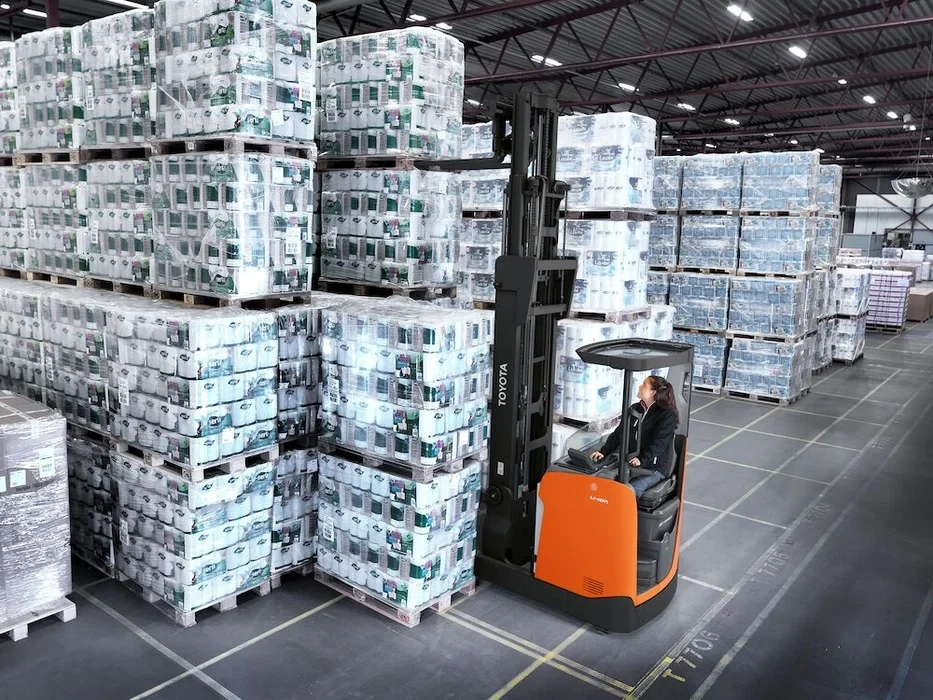 BT Reflex RRE160HN reach truck with narrow chassis. Application photo in warehouse environment. 