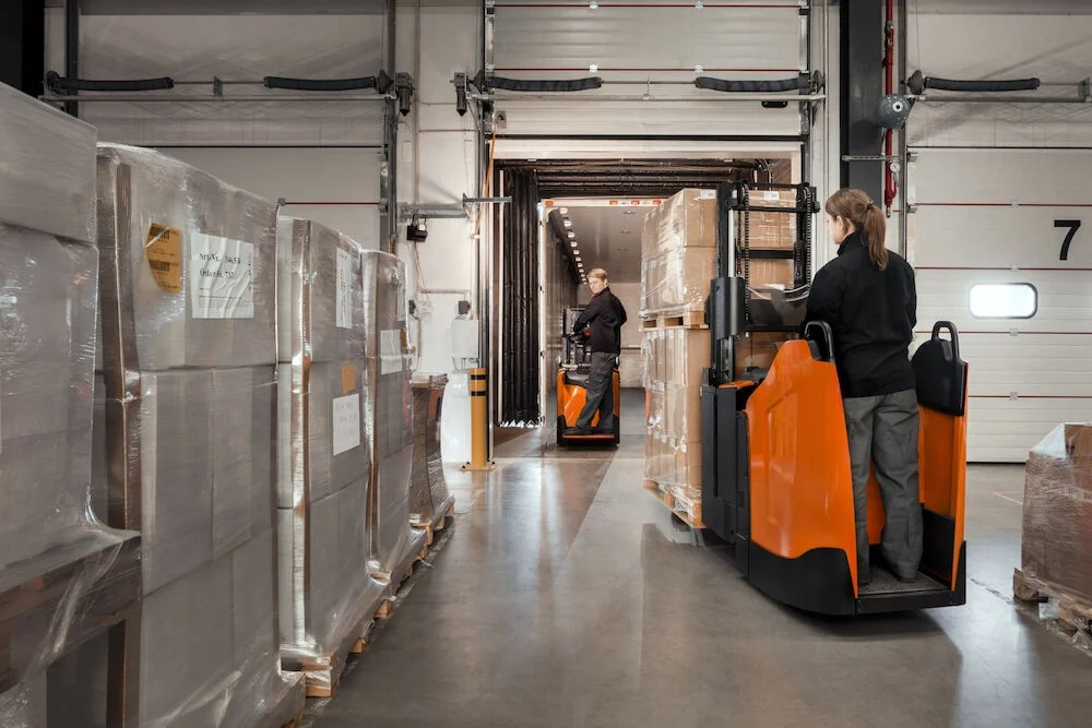 BT Staxio SPE200DN, electric stacker with double load handling and fixed side guards. Application photo in loading bay.