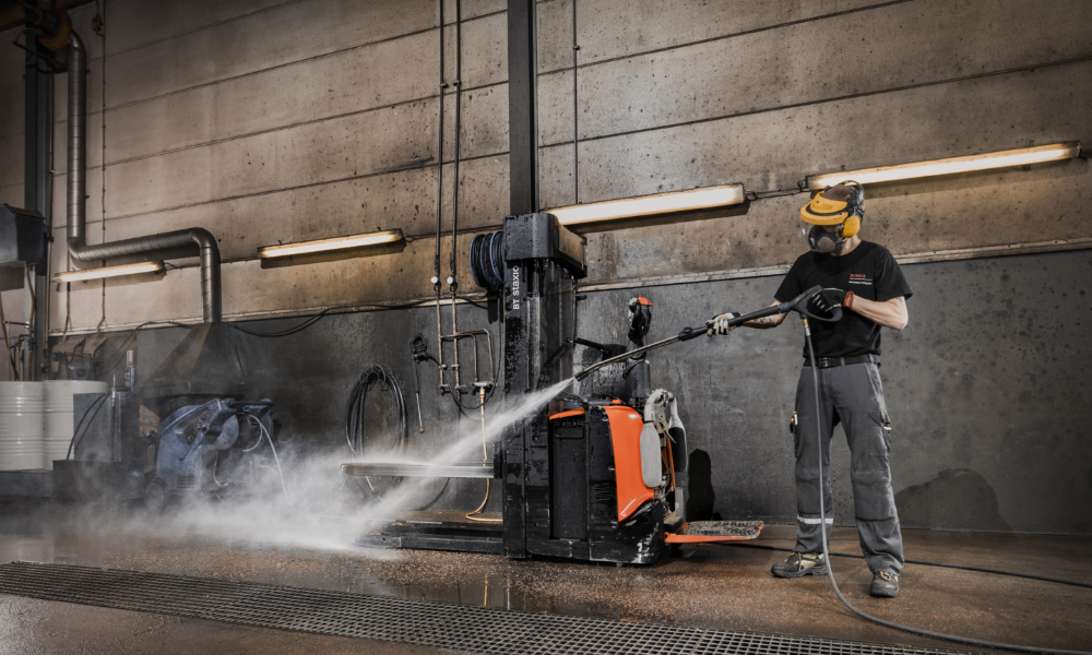 Employee washing used Toyota powered stacker with pressure washer