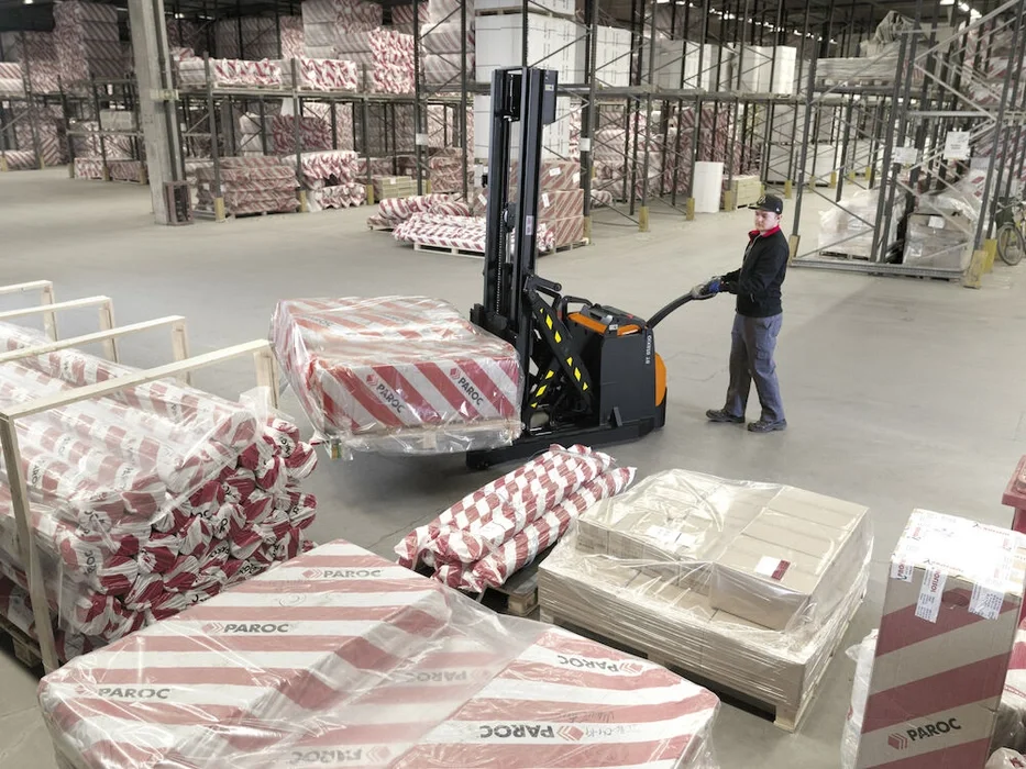BT Staxio SWE120XR, electric walkie stacker with reach mast. Application photo in warehouse environment.