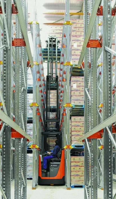 BT Reflex RRE160HN reach truck with narrow chassis. Application photo in warehouse environment. 