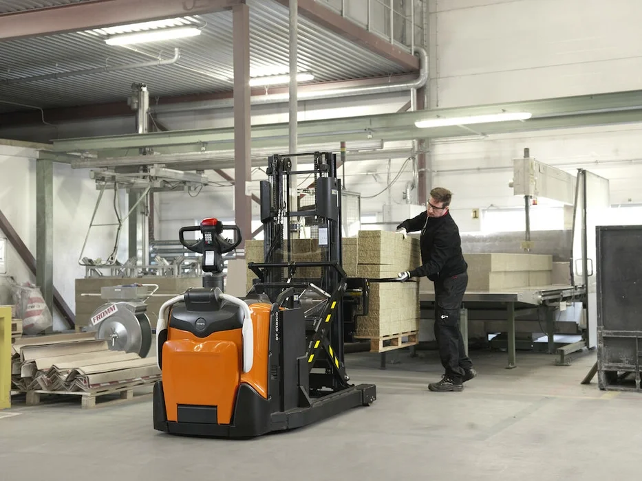 BT Staxio SPE120XR, electric stacker with reach mast, platform, and side guards. Application photo in a warehouse environment.