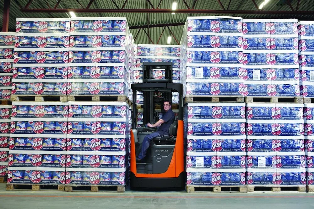 BT Reflex RRE160HN reach truck with narrow chassis. Application photo in warehouse environment. 