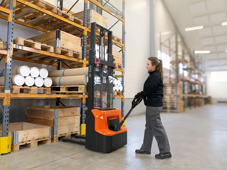 BT Tyro SHE100 walkie operated powered stacker. Application photo of stacking in a warehouse environment.