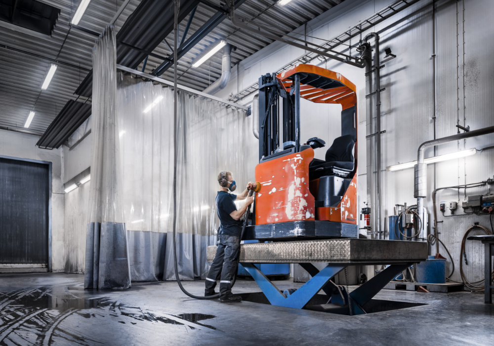 Employee refurbishing used Toyota reach truck in workshop